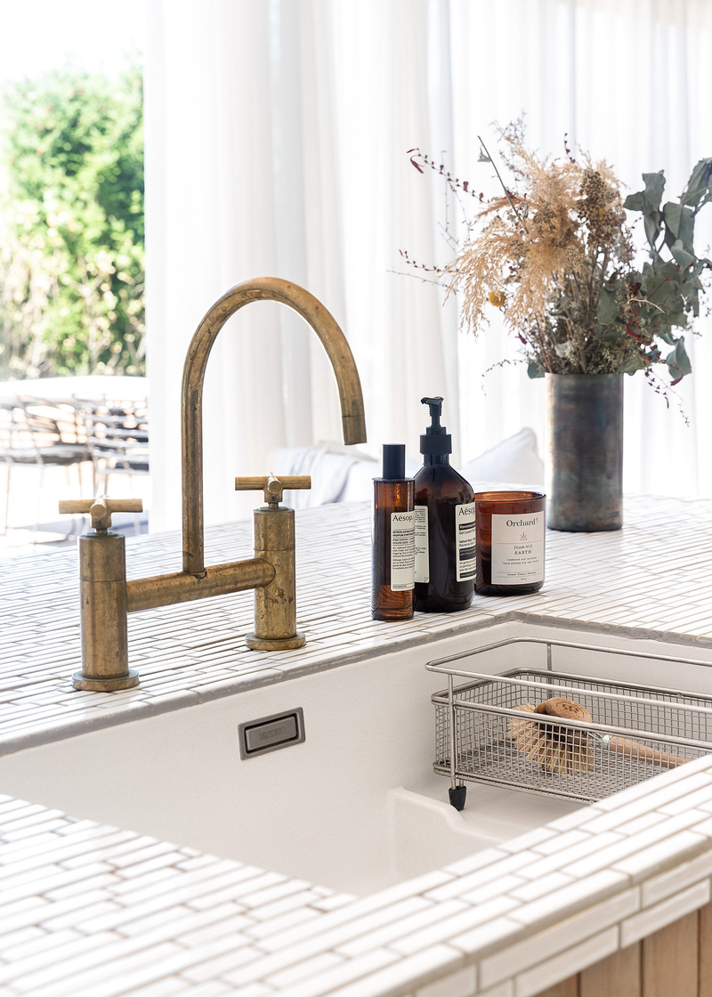 A sink in a kitchen with a brass faucet from "Our Spaces - Contemporary New Zealand Interiors" by Books.