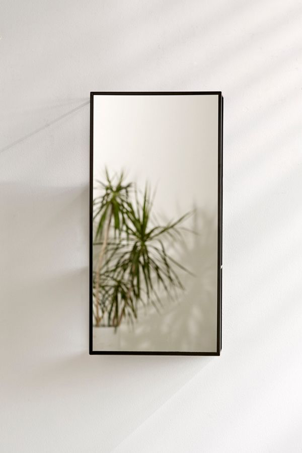 Umbra Cubiko mirror and storage unit in black on a white wall beside a plant