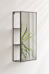 A small space living mirror from the Umbra range, featuring the Cubiko Mirror & Storage Unit - Black design, adorned with a plant.