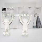 A pair of Buddy Over The Door Hook White figures from Umbra range hanging on a wall.