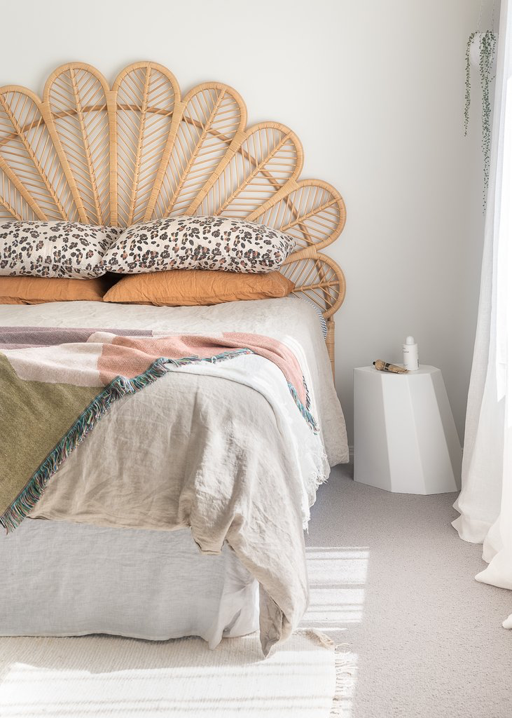 A bed with a rattan headboard and pillows from Our Spaces - Contemporary New Zealand Interiors brand.