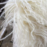 A close up of a white sheep with long hair, showcasing Flux Home's Tibetan Lamb Fur Double Rug.