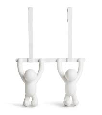 A pair of white BUDDY OVER THE DOOR HOOK WHITE figurines from the Umbra range, hanging on a white wall.