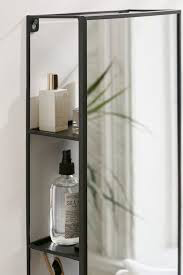 Close-up of the Umbra Cubiko mirror and storage unit shelves holding toiletries