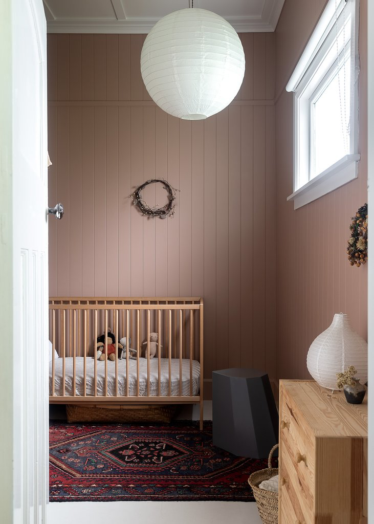 A baby's room with a Our Spaces - Contemporary New Zealand Interiors rug and a crib from Books.