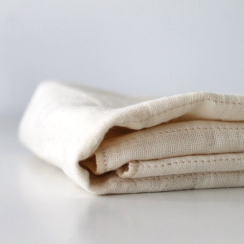 A NAWRAP ORGANIC MINI TOWEL - IVORY from Flux Home on a white surface.