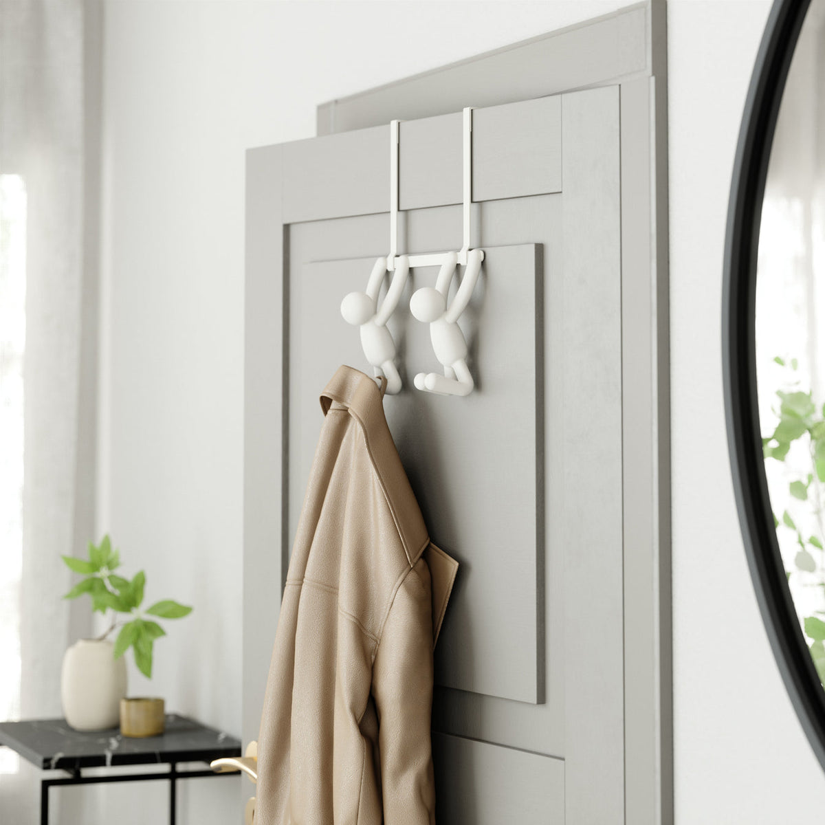 Umbra Buddy over-the-door double hook in white holding a coat