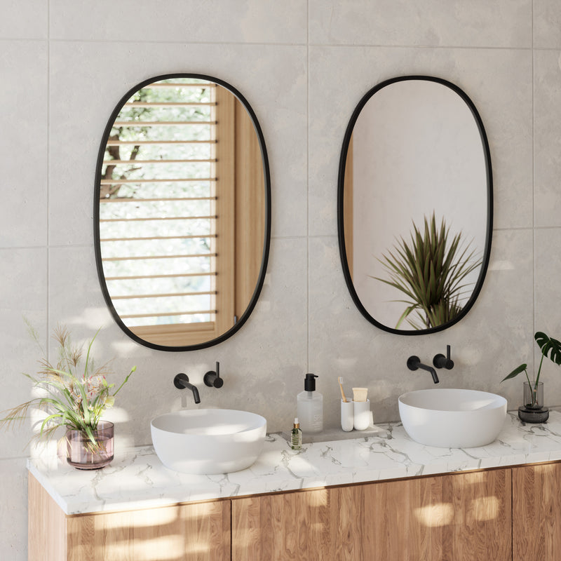 A bathroom with two sinks and two mirrors featuring the Hub Mirror Oval - Black from the Umbra range, each mirror adorned with a stylish rubber rim.