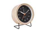A Karlsson Alarm Innate - Various Colours with a black and white design and wood casing, placed on a stand.