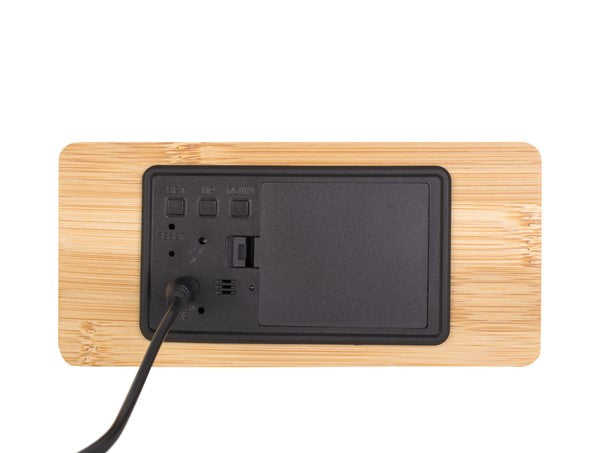 A minimal Karlsson clock charging station with a power cord attached to it.
