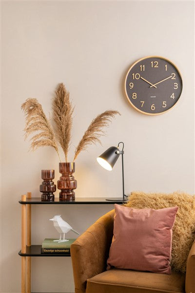 Karlsson Pure Wall Clock mounted on the wall of a living room with a brown armchair