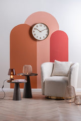 A minimal living room with an orange wall and a Karlsson clock.