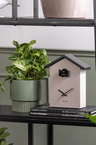 A Cuckoo Traditional - Various Options clock by Karlsson on a shelf next to a potted plant.