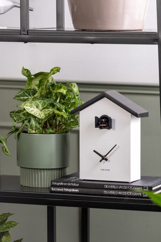 A Cuckoo Traditional - Various Options wall clock by Karlsson next to a potted plant on a shelf.
