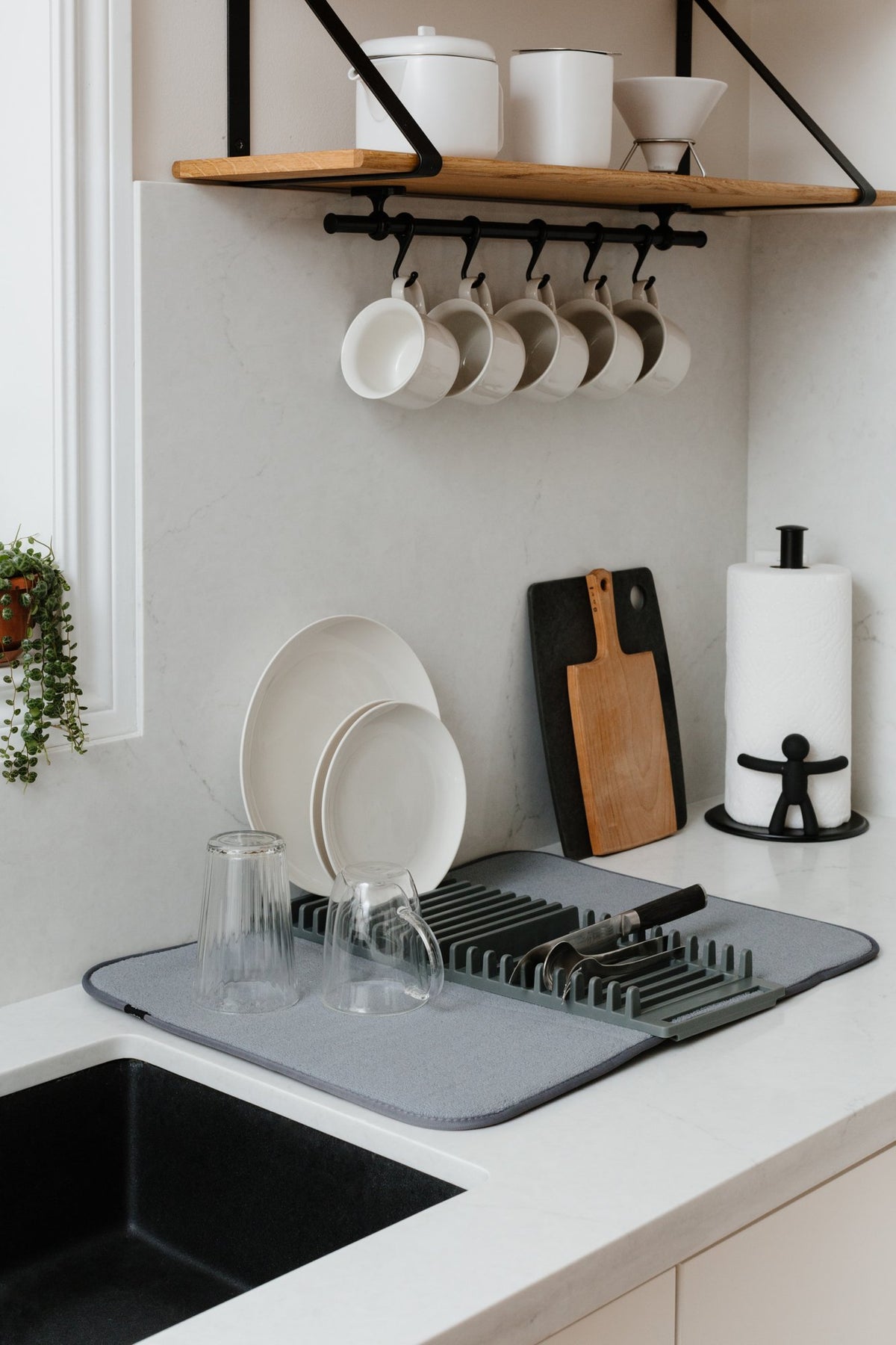 Umbra Udry dish rack in a kitchen beside the sink, plates and glasses drying