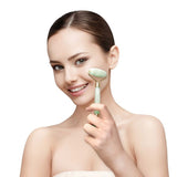 A woman is holding a green Crystal Facial Roller from Albi, using it to revitalise her skin tone while smiling.