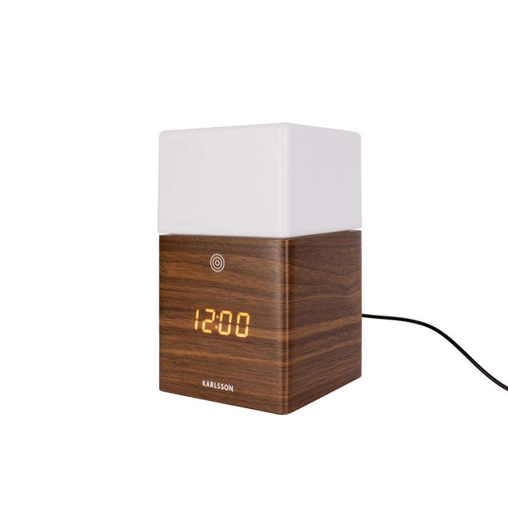 Karlsson Frost Light Alarm Clock illuminated, styled on a bedside surface