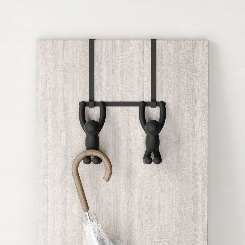 A Umbra Buddy Over-the-Door Hook with a black coat hanger and an umbrella hanging on it.