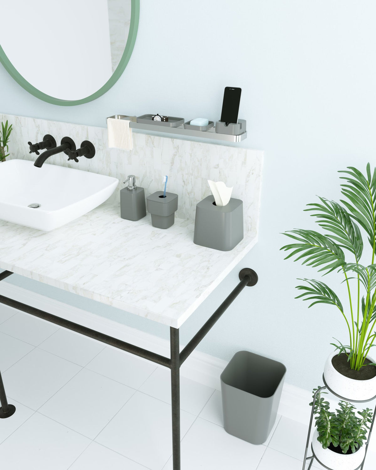 Marble vanity with charcoal SCILLAE bathroom accessories, a wastebasket and potted palms