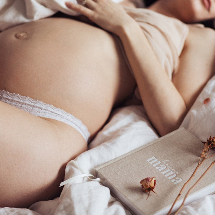 A pregnant woman journaling her journey with the Becoming MAMA - A Pregnancy Journal, a perfect baby shower gift.