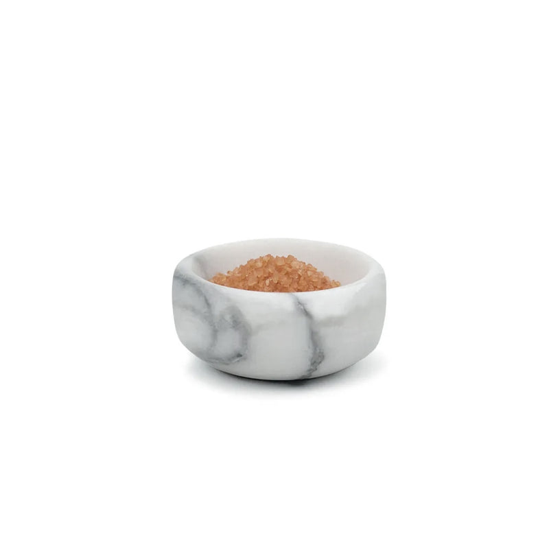 A small bowl of Dishy gourmet salts, called the White Marble Spice Bowl, on a white surface.