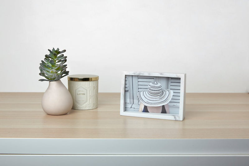 A white dresser with an Umbra Edge Marble Frame and a plant on it.