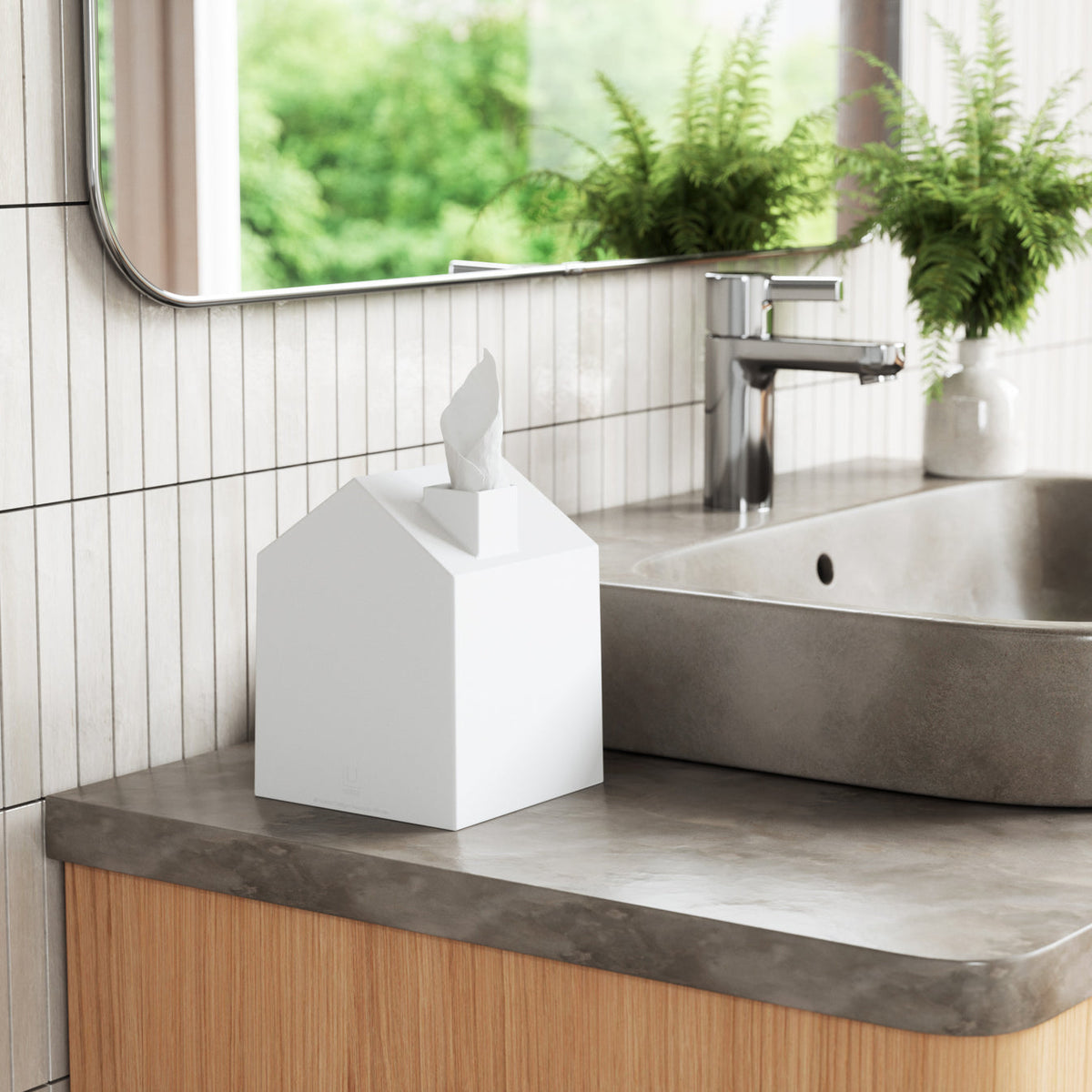 Umbra Casa white house-shaped tissue box cover on a stone vanity beside a basin