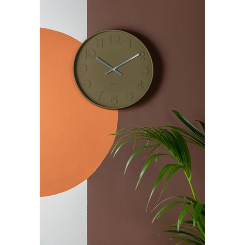 An aesthetically pleasing Karlsson wall clock enhancing the design of an orange wall, adorned with a vibrant plant.