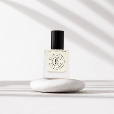 Perfume oil bottle sitting on a smooth white stone in soft light