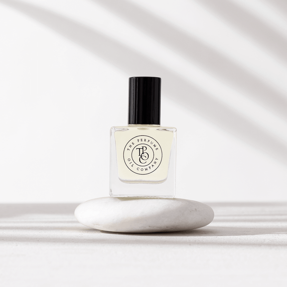 Perfume oil bottle on a smooth white stone in soft shadows