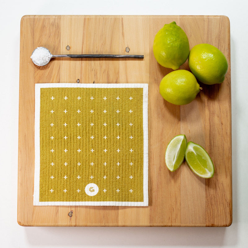 Limes and lemons on a cutting board next to an ECO CLOTH - MEDIUM (3-PACK) featuring modern designs, branded by Good Change.
