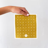 A hand holding a Good Change ECO CLOTH - MEDIUM (3-PACK) yellow polka dot towel.