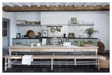 A kitchen with "For The Love Of White: The White & Neutral Home" books placed on a wooden bench and wooden beams.