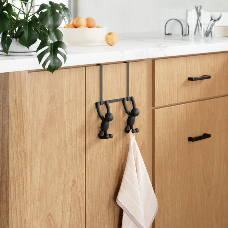 A kitchen with an Umbra Buddy Over the Door Hook Black hanging on the wall.