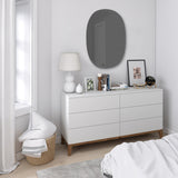 A Hub Mirror - Bevy Oval 24X36 - Smoke by Umbra dresser and mirror with a copper finish in a bedroom.