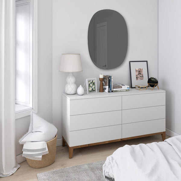 A Hub Mirror - Bevy Oval 24X36 - Smoke by Umbra dresser and mirror with a copper finish in a bedroom.