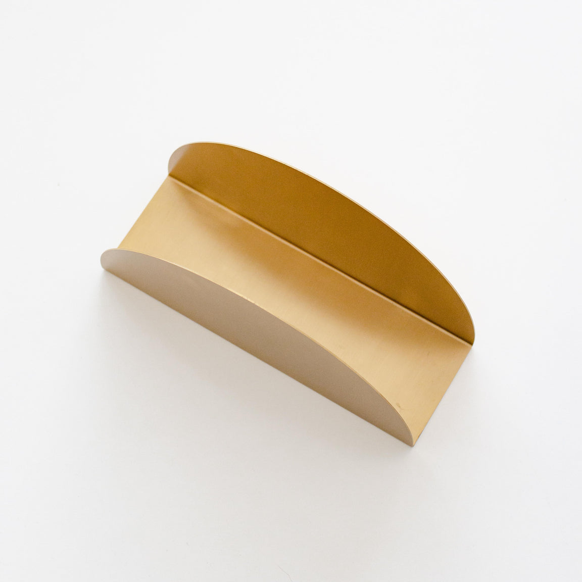 Solid brass arched book holder styled on a desk with books