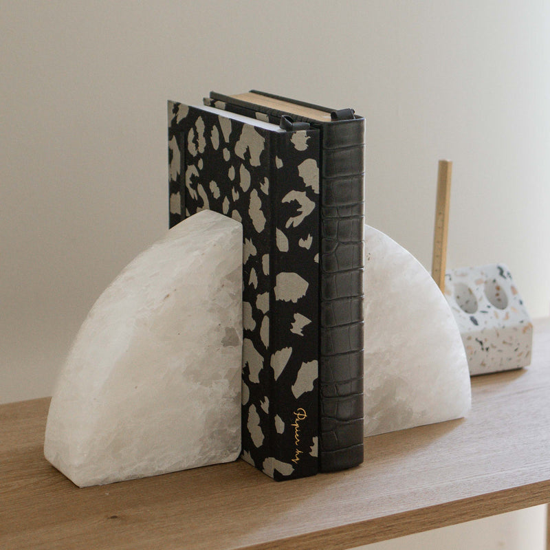 A limited edition stationery range featuring Stone Rounded Bookends by Papier HQ on a wooden shelf.
