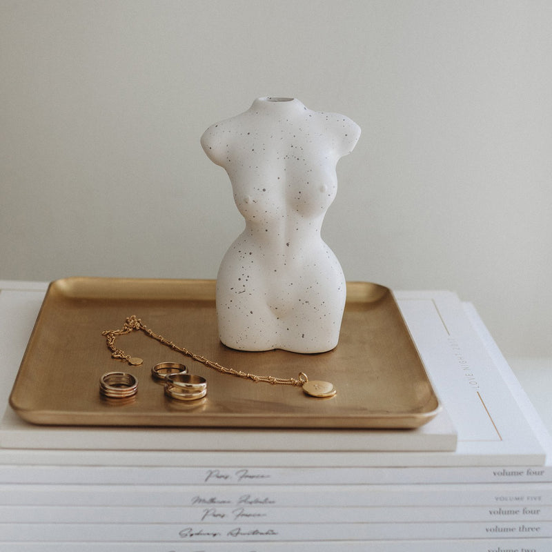 A white mannequin sitting on a Papier HQ brass tray.