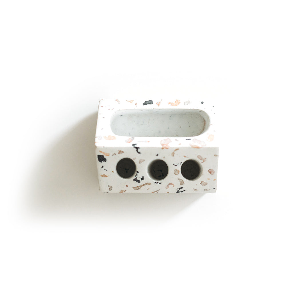 Terrazzo pen holder with a long slot and three round holes, on white