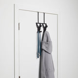 An Umbra Buddy Over the Door Hook Black, featuring a friendly Buddy design, hanging on a door.