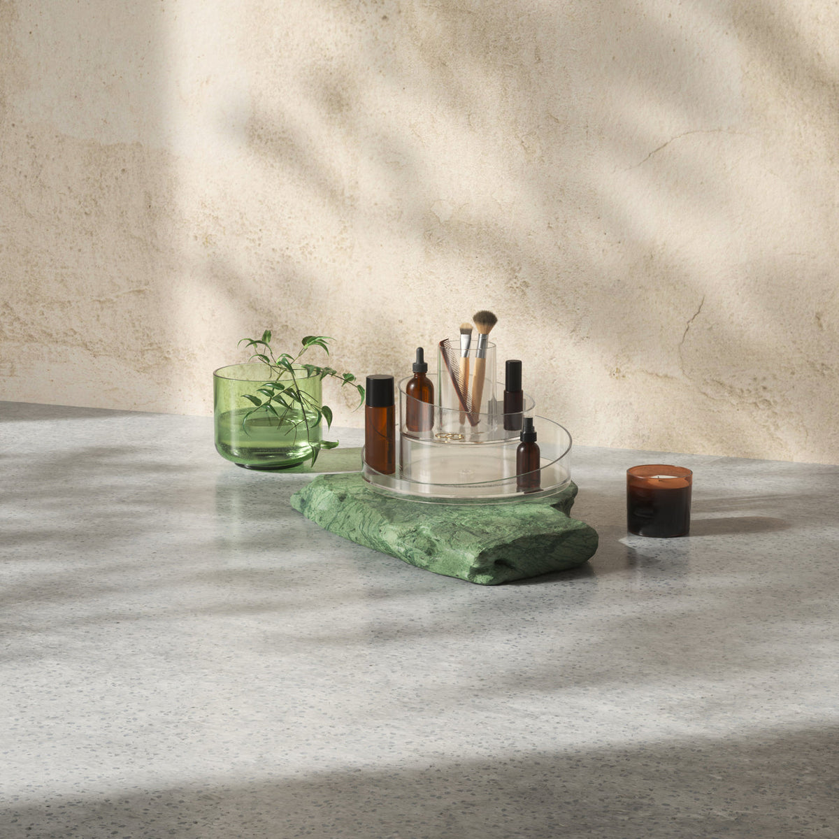 A table with a green plant and the Umbra Cascada Cosmetic Organizer on it.