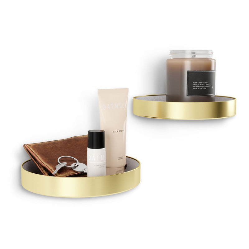 An Umbra Perch Shelf Set-of-2 - Brass, adorned with a candle and cosmetics.