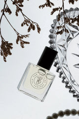 Rouge inspired fragrance in clear square glass bottle with black cap styled on reflective surface