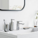 A bathroom with a white sink, mirror, and Umbra Junip Oval Soap Dish - Stainless Steel.
