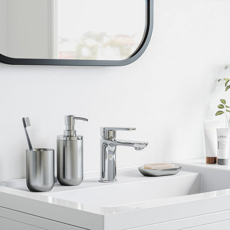 A bathroom with a white sink, mirror, and Umbra Junip Oval Soap Dish - Stainless Steel.