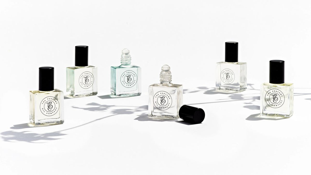 Several uncapped perfume oil bottles spread across a white surface