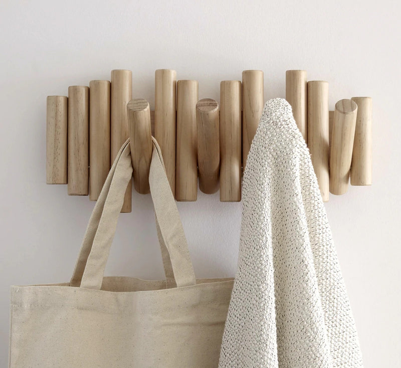 A wooden coat rack from the Umbra range with a Picket Rail Five Hooks, serving as wall art, and featuring a tote bag hanging on it.