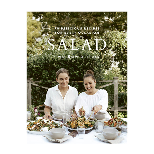 Two women are sitting at a table and eating a salad from the brand "Books," which offers 70 delicious recipes for every occasion.