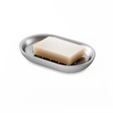 A Junip Oval Soap Dish - Stainless Steel from the Umbra Junip Collection on a white surface.